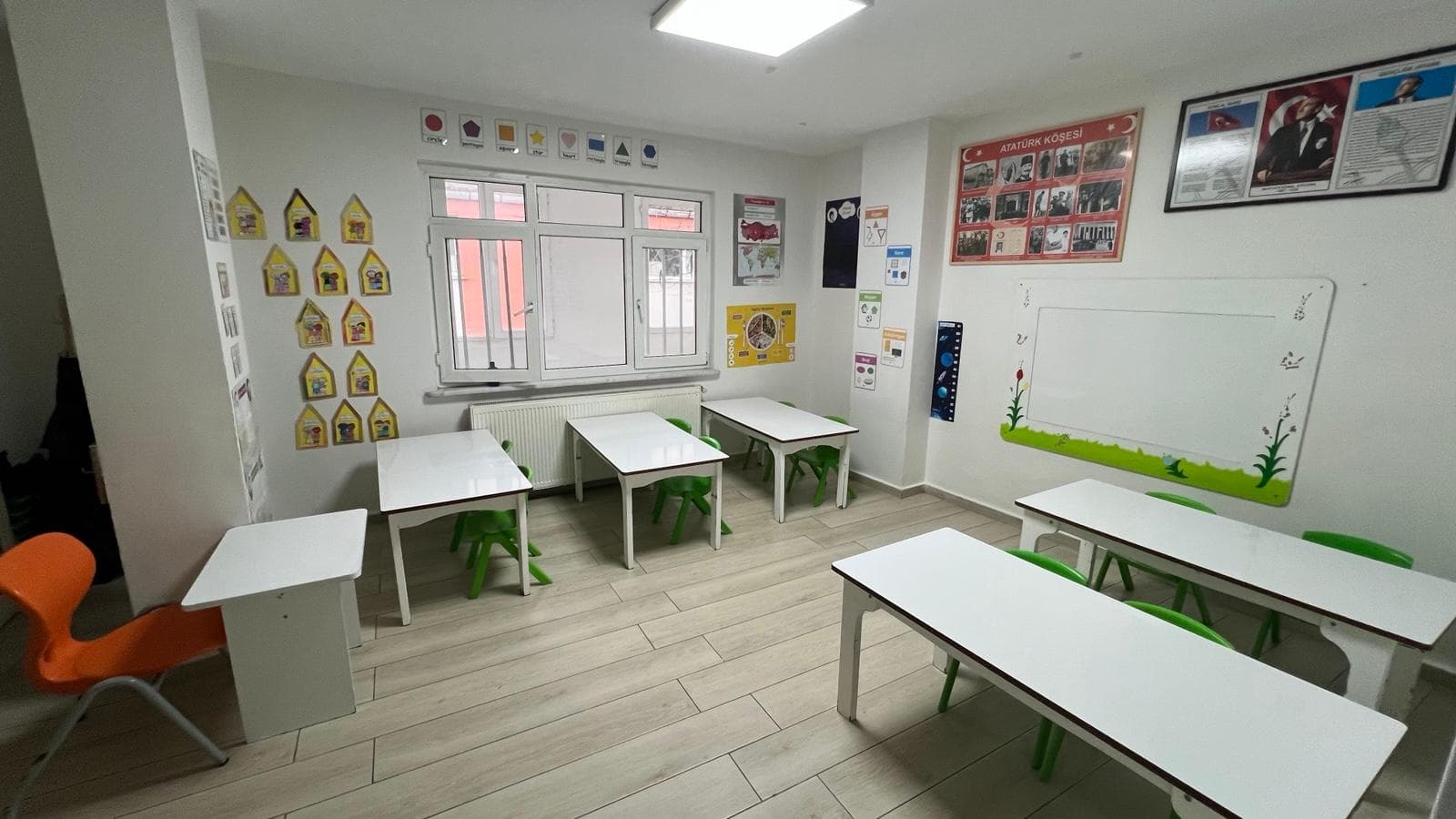 Anaokulu sınıfı — minik masa-sandalyeler, şekiller panosu ve Atatürk köşesi